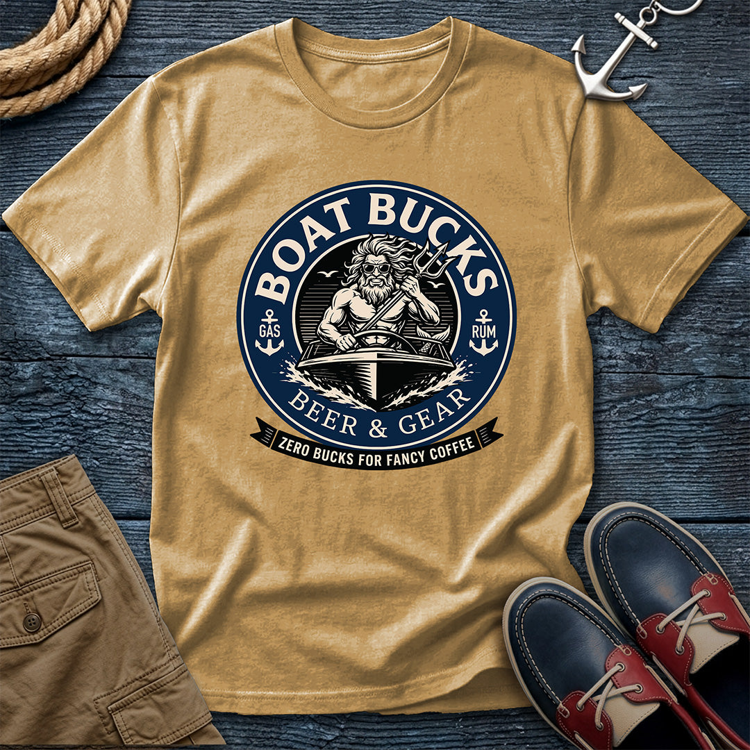 Mustard short-sleeve crewneck t-shirt with a circular navy graphic reading 'Boat Bucks Beer & Gear' featuring a trident-wielding sea god in a speedboat and the tagline 'Zero Bucks For Fancy Coffee', styled on a nautical flatlay with rope, anchor, boat shoes, and khaki shorts.
