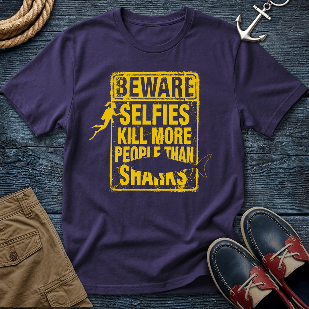 Purple t-shirt with yellow text and graphics on a wooden surface with accessories.