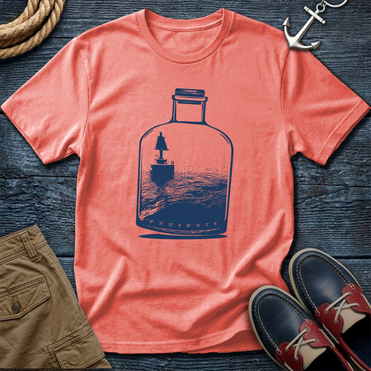 Coral t-shirt with a Channel Marker in a bottle graphic on a wooden surface with shorts and shoes.