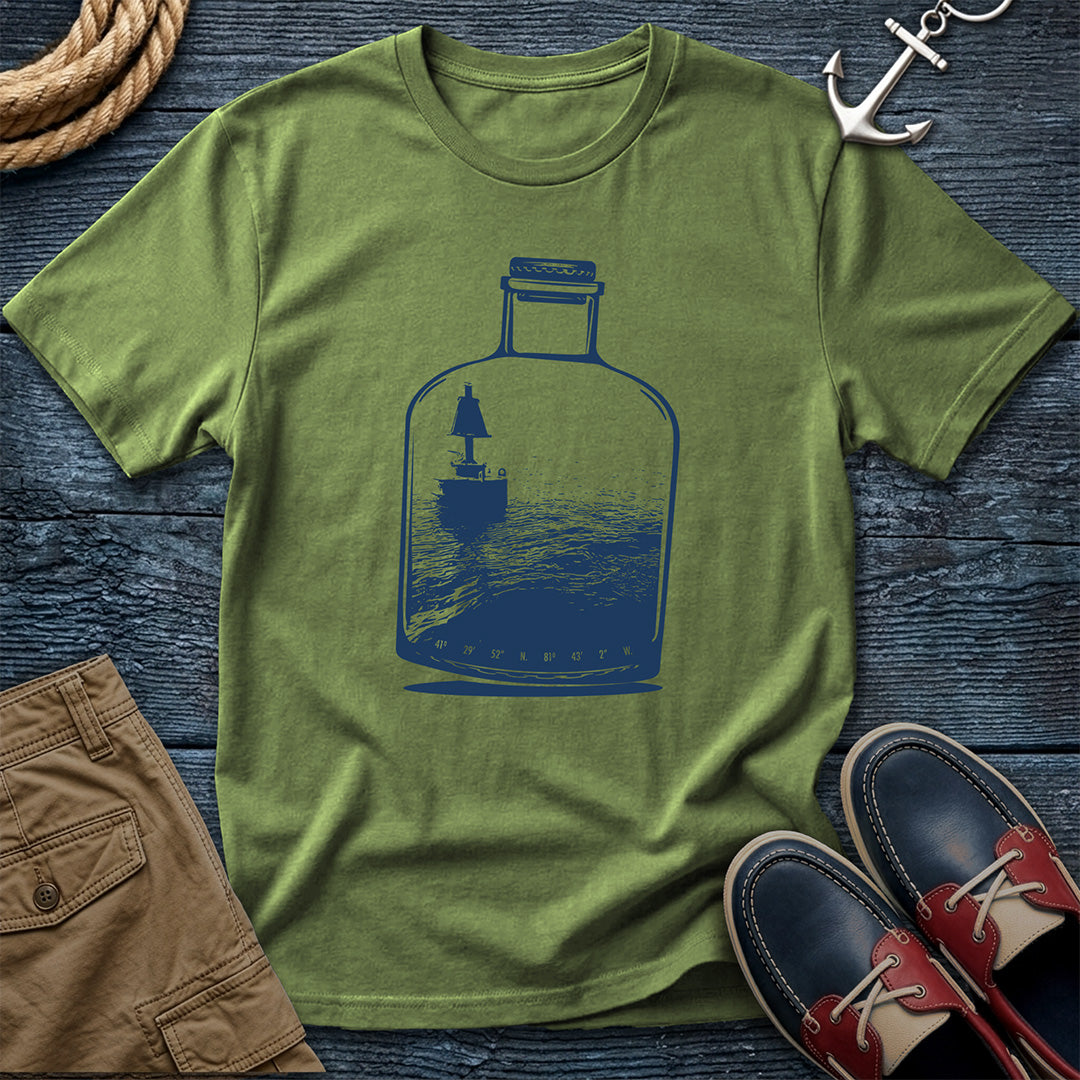 Green t-shirt with a blue bottle graphic on a wooden surface with shoes and rope.