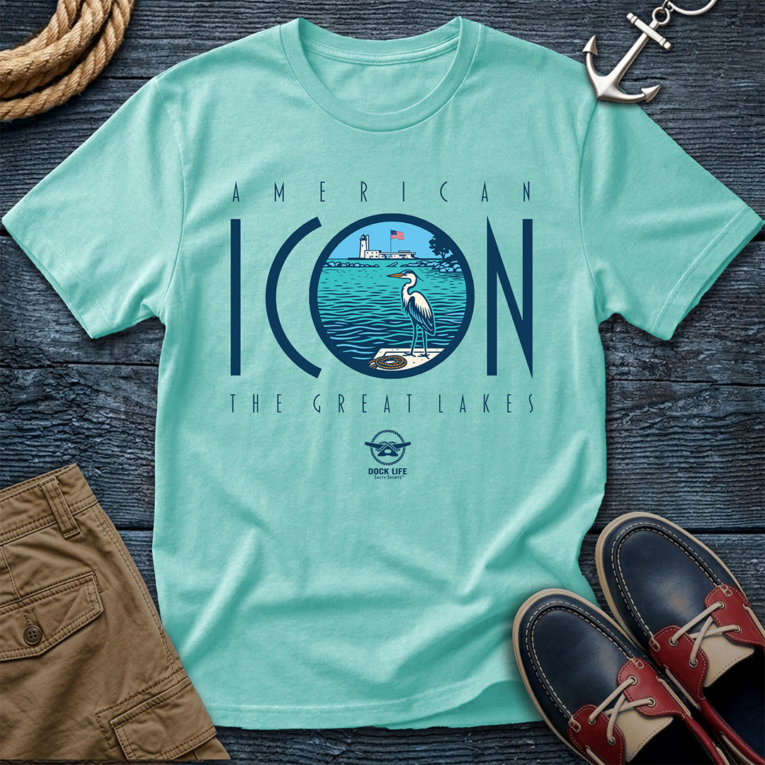 Light blue t-shirt with 'American Icon The Great Lakes' design on a wooden surface with shorts and shoes.