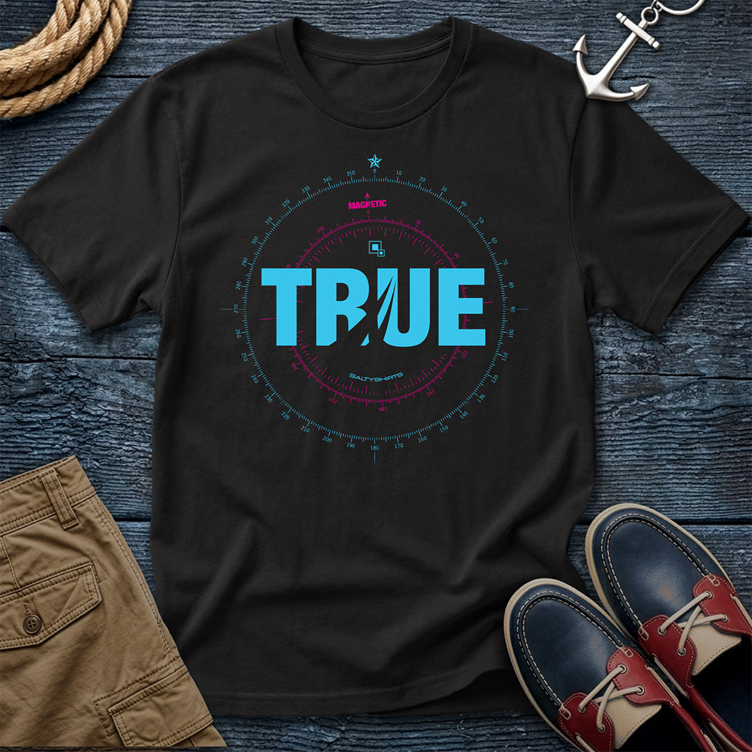 Black t-shirt with 'TRUE' Compass Rose design on a wooden surface with shorts and shoes.