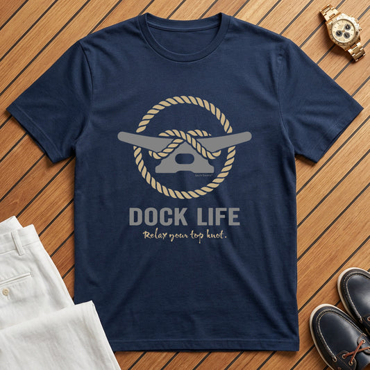 Navy blue t-shirt with 'Dock Life' graphic on a wooden surface with boat shoes and white pants.