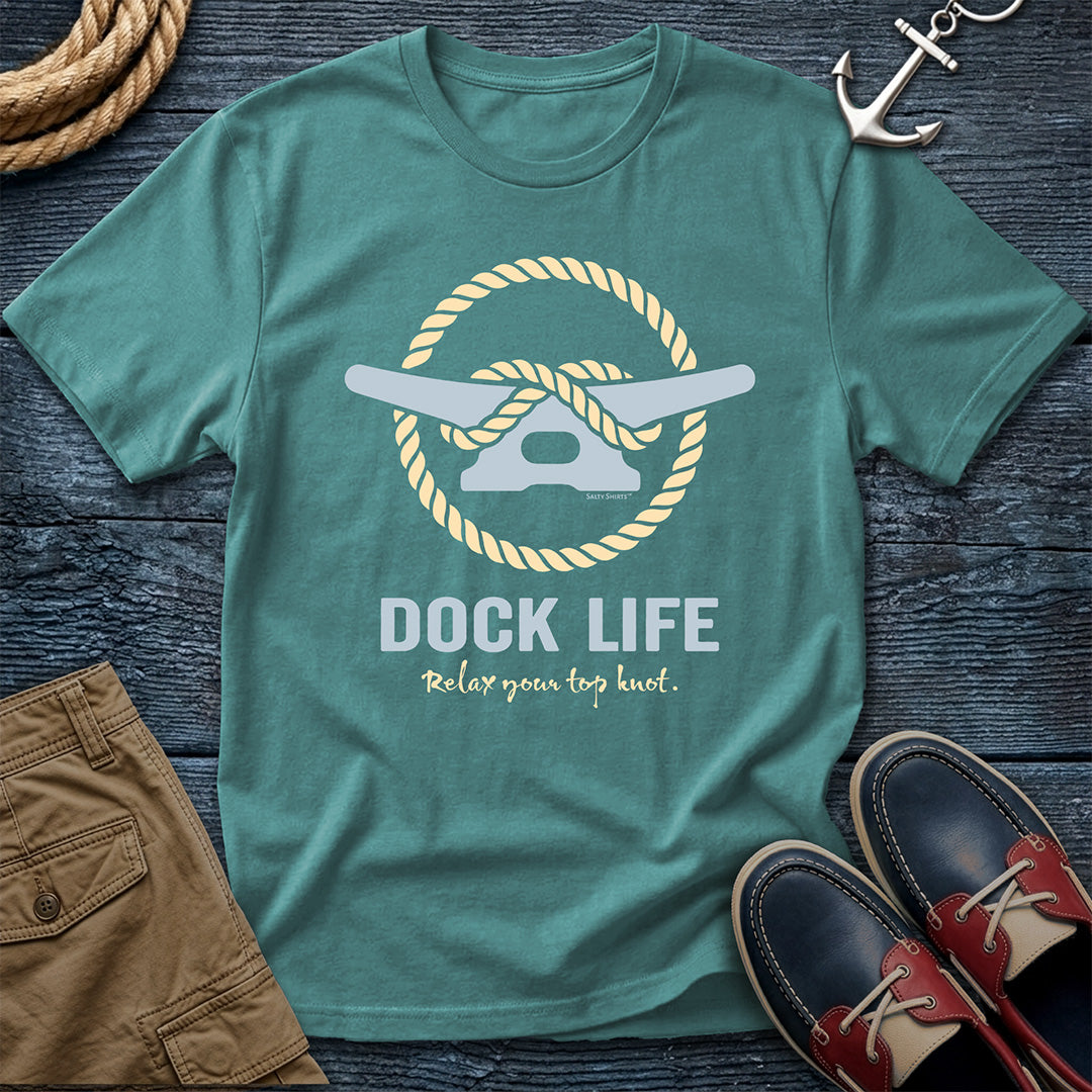Teal t-shirt with 'Dock Life' graphic on a wooden surface with shoes and shorts.