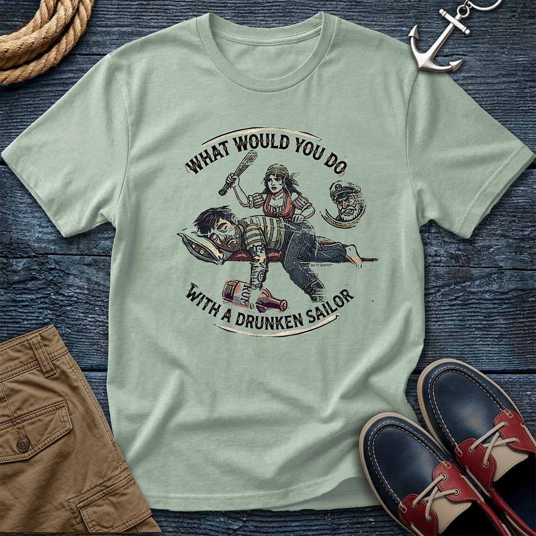 Drunken Sailor Shanty Tee in Bay: flat lay of a Comfort Colors 1717 tee on dark weathered wood with rope, an anchor keychain, khaki pants, and boat shoes. Distressed woodcut print shows a woman with a club swinging at a passed-out drunken sailor holding a rum bottle, framed by the text "What Would You Do With a Drunken Sailor."