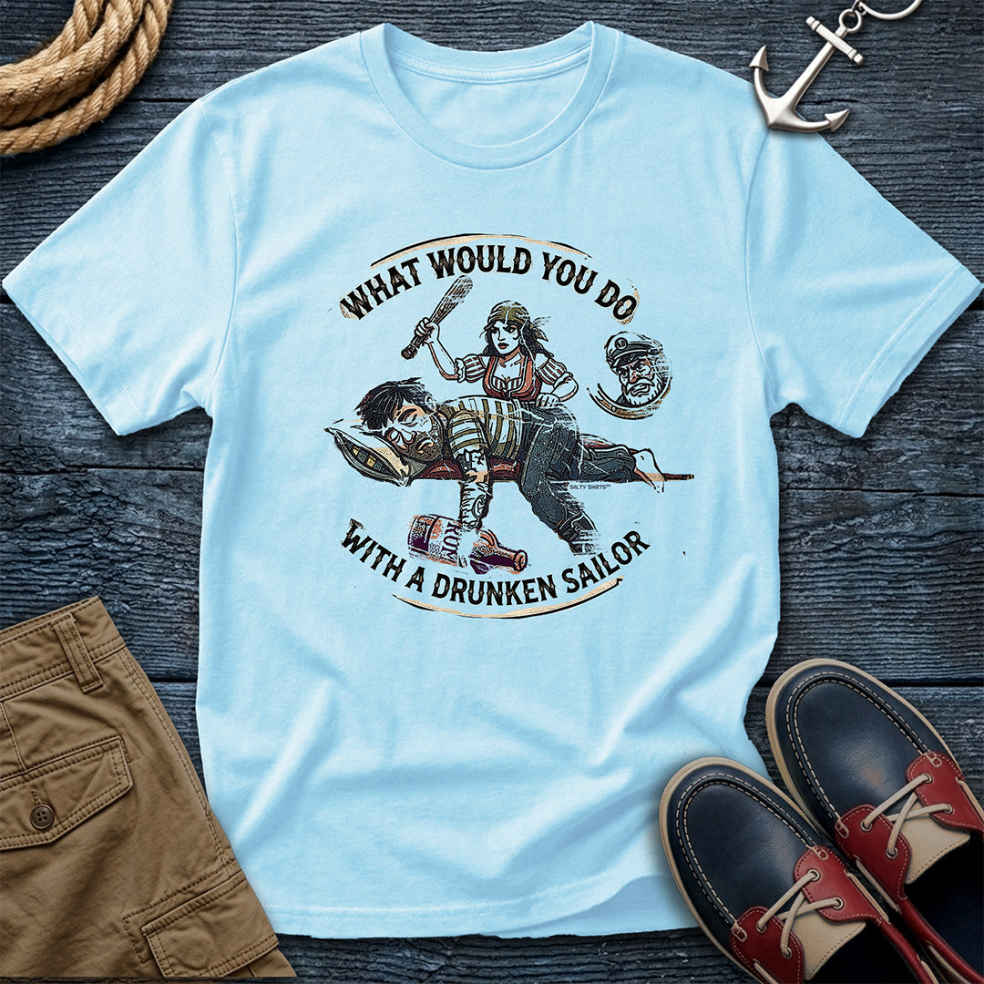 Drunken Sailor Shanty Tee in Chambray: flat lay of a Comfort Colors 1717 tee on dark weathered wood with rope, an anchor keychain, khaki pants, and boat shoes. Distressed woodcut print shows a woman with a club swinging at a passed-out drunken sailor holding a rum bottle, framed by the text "What Would You Do With a Drunken Sailor."