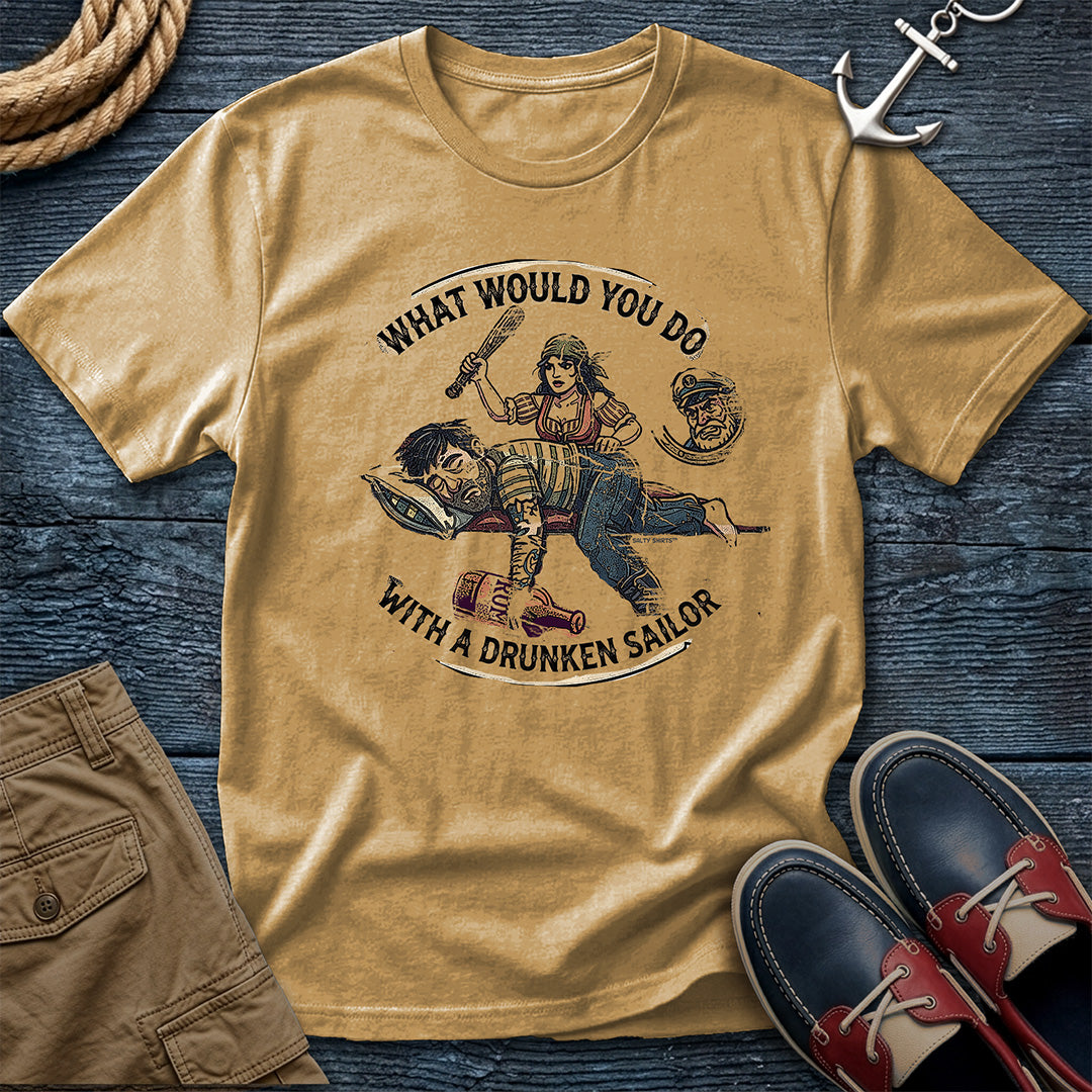 Drunken Sailor Shanty Tee in Mustard: flat lay of a Comfort Colors 1717 tee on dark weathered wood with rope, an anchor keychain, khaki pants, and boat shoes. Distressed woodcut print shows a woman with a club swinging at a passed-out drunken sailor holding a rum bottle, framed by the text "What Would You Do With a Drunken Sailor."