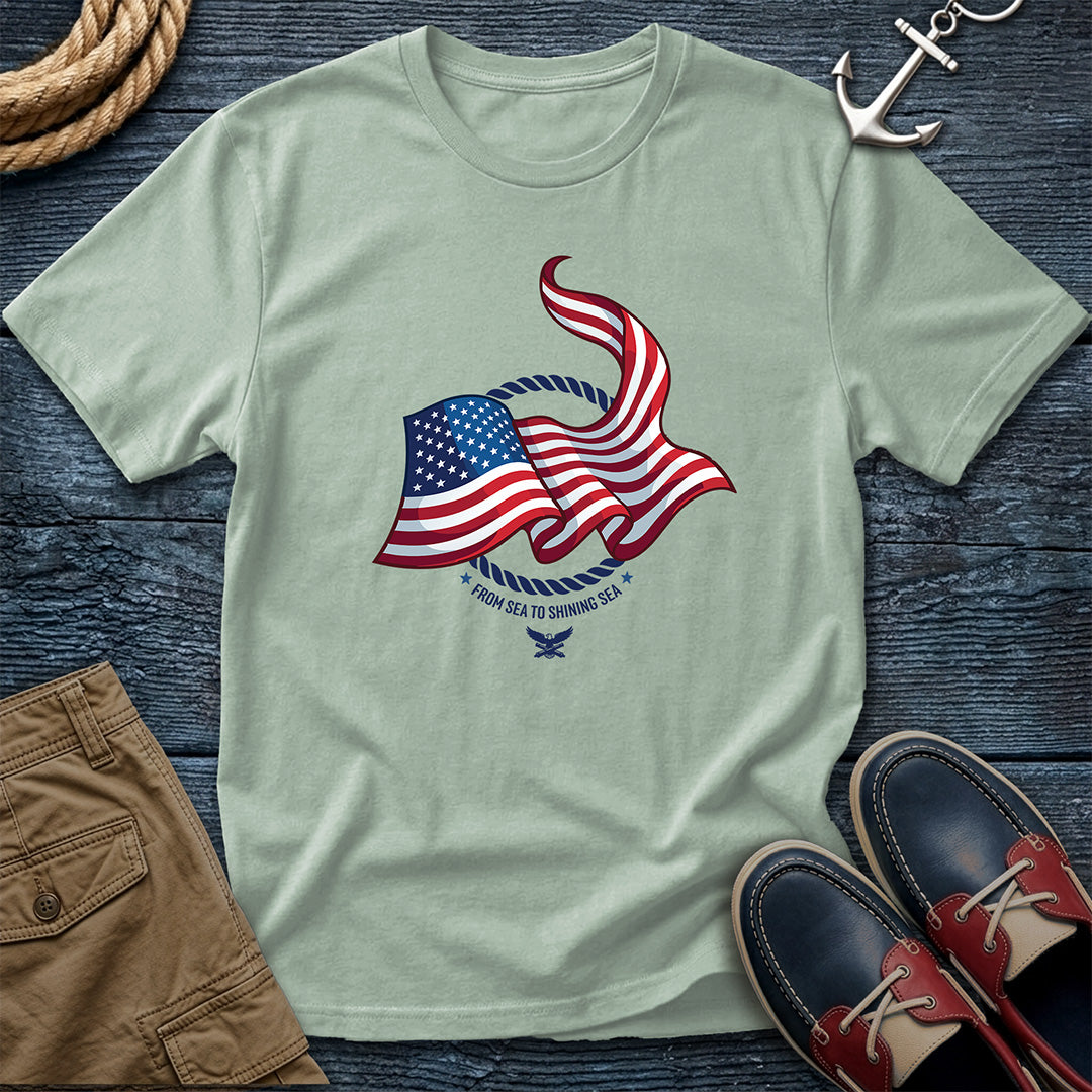 From Sea to Shining Sea American Flag Tee in Bay, Comfort Colors 1717 garment-dyed shirt with a waving American flag inside a rope ring, curved text, and eagle-and-anchors mark

