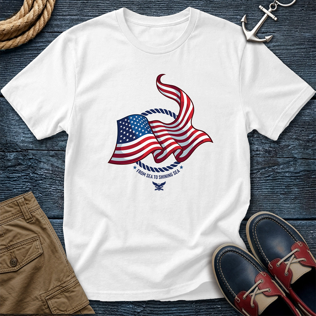 From Sea to Shining Sea American Flag Tee in White, Comfort Colors 1717 garment-dyed shirt with a waving American flag inside a rope ring, curved text, and eagle-and-anchors mark.