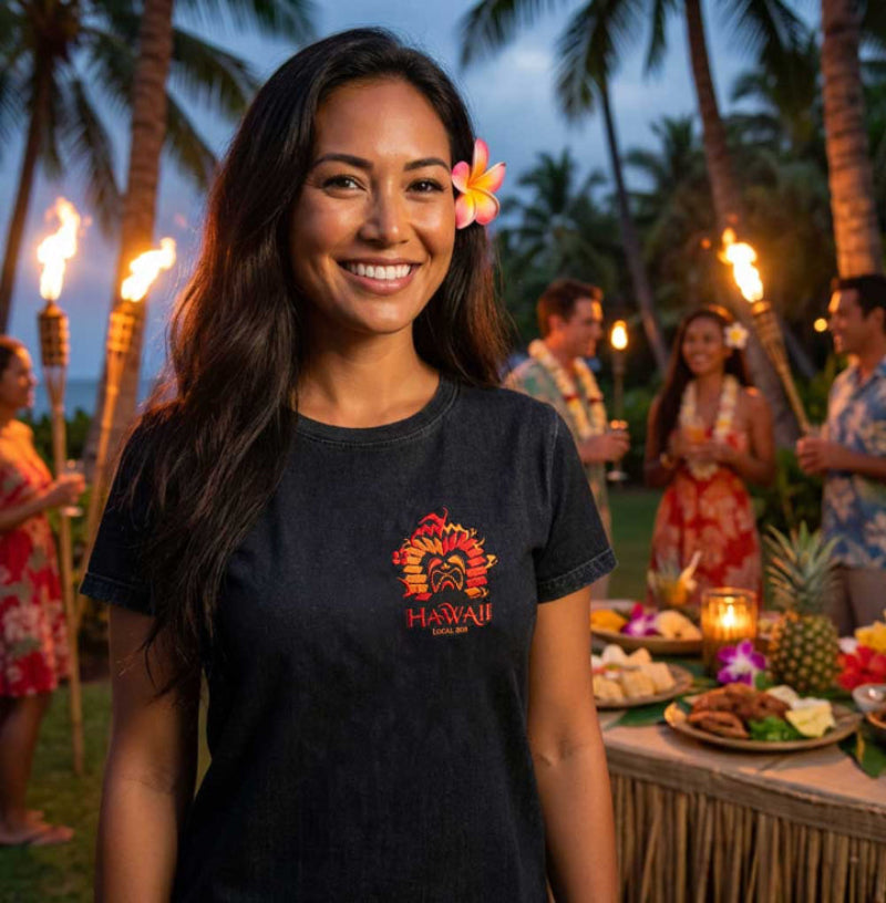 Woman wearing a black t-shirt with a Hawaii logo at a tropical outdoor event.