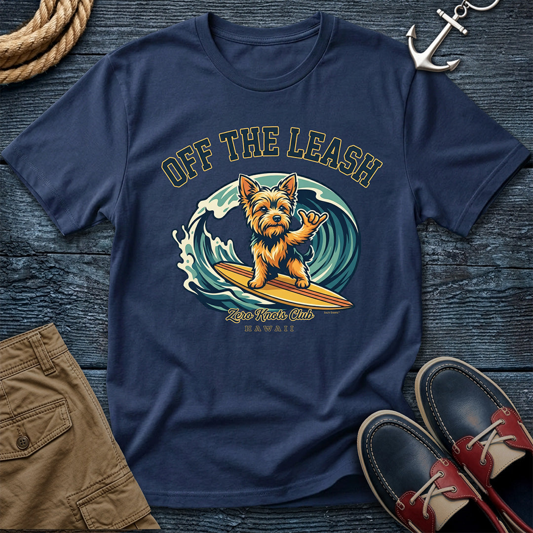 Navy blue t-shirt with a dog surfing graphic on a wooden surface with shorts and shoes.