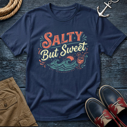 Navy blue t-shirt with 'Salty But Sweet' design on a wooden surface with shorts and shoes.