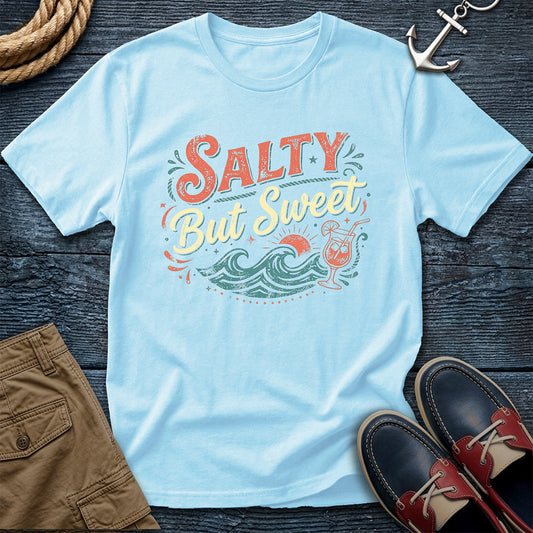 Light blue t-shirt with 'Salty But Sweet' design on a wooden surface with shorts and shoes.