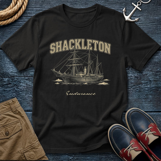 Black t-shirt with Shackleton and Endurance design on a wooden surface with shorts and shoes.
