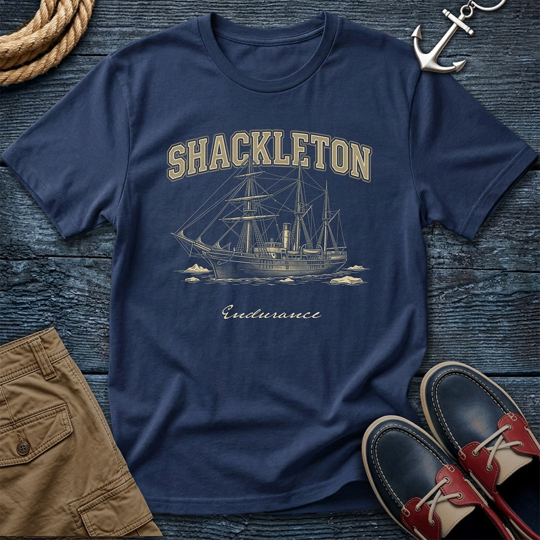 Navy blue t-shirt with Shackleton Endurance graphic on a wooden surface with shorts and shoes.