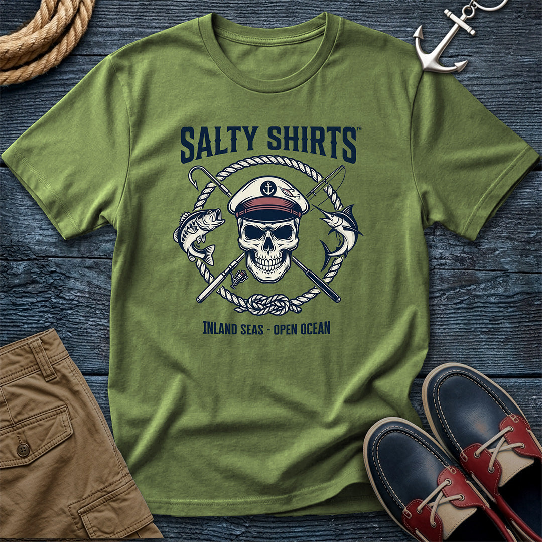 Green t-shirt with skull and rope design on a wooden surface with shorts and shoes.