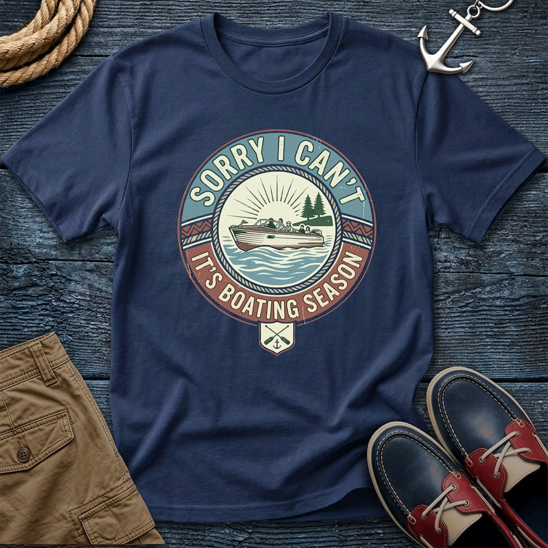 Navy blue t-shirt with boating season graphic on a wooden surface with shorts and shoes.