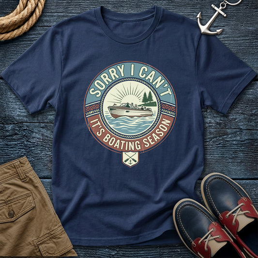 Navy blue t-shirt with boating season graphic on a wooden surface with shorts and shoes.