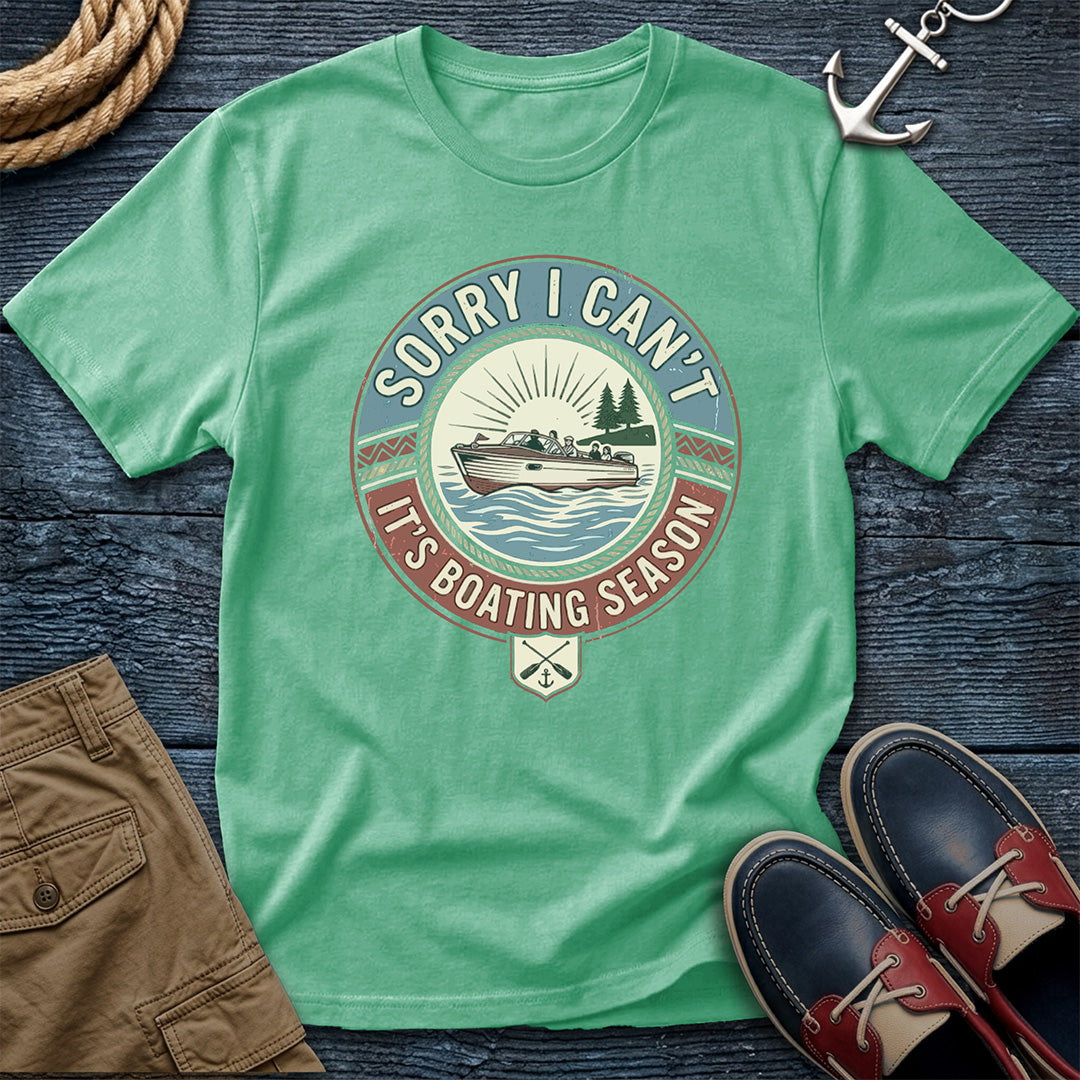 Green t-shirt with boating season graphic on a wooden surface with shorts and shoes.