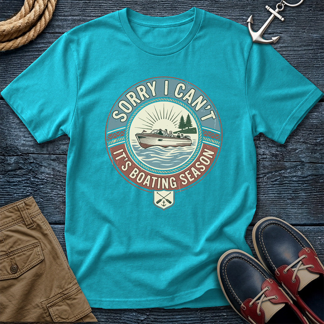 Blue t-shirt with boating season graphic on a wooden surface with shorts and shoes.