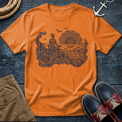 Sunrise Shore Meditation Tee in Orange, Comfort Colors 1717 garment-dyed shirt with a seated shoreline figure, rising sun, geometric mandala, waves, shells, kelp, and circling gulls.
