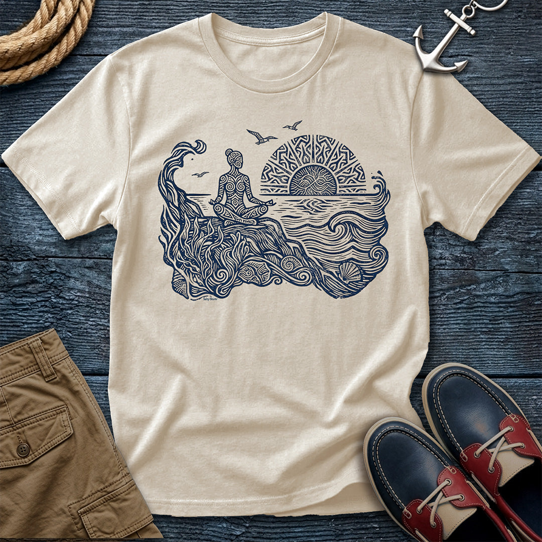 Sunrise Shore Meditation Tee in Ivory, Comfort Colors 1717 garment-dyed shirt with a seated shoreline figure, rising sun, geometric mandala, waves, shells, kelp, and circling gulls.