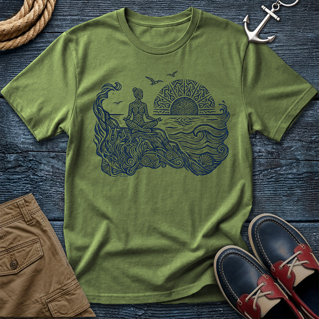 Sunrise Shore Meditation Tee in Sage, Comfort Colors 1717 garment-dyed shirt with a seated shoreline figure, rising sun, geometric mandala, waves, shells, kelp, and circling gulls.