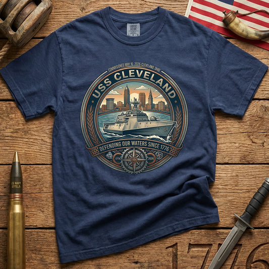 Navy t-shirt with USS Cleveland graphic on a wooden surface with American flag powder shel old blocks and knife carve 1776